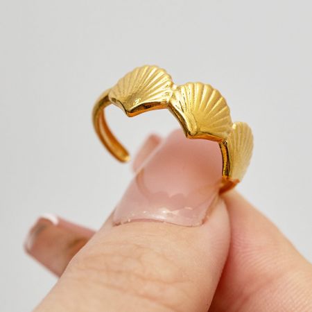 Close-up van de gouden schelp ring, die het gedetailleerde ontwerp toont.
