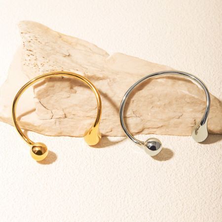 Bovenaanzicht van de gouden en zilveren cuff bangles die op een steen rusten.