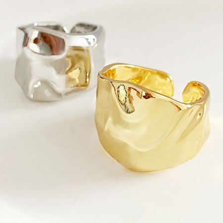 A pair of gold and silver hammered geometric open rings displayed together.