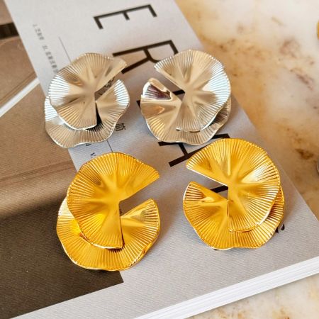 Vier paar bloemvormige statementoorbellen in goud en zilver.