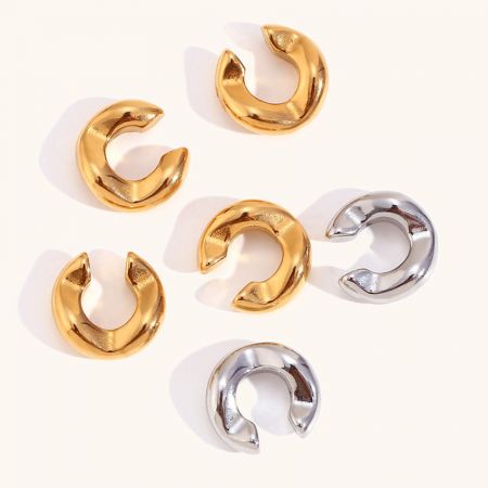 A collection of gold and silver stainless steel ear cuff earrings shown together.