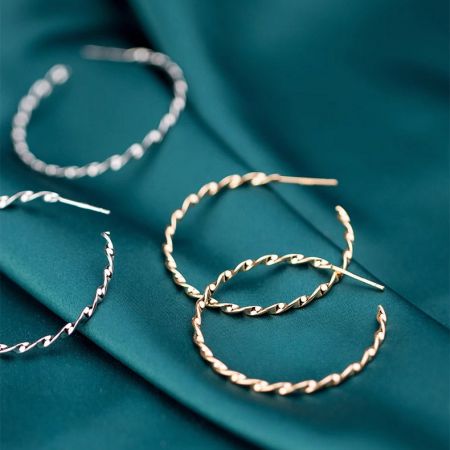 925 Zilveren gedraaide touw C-hoepel oorbellen - Een collectie van 925 sterling zilveren gedraaide touw C-hoepel oorbellen in zowel gouden als zilveren afwerkingen, elegant gepresenteerd op een gestructureerde teal stof.