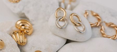 A collection of gold and silver jewelry, highlighting interlocking ring earrings, representing our wholesale offerings.