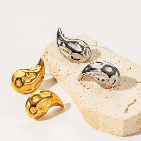Vista superior de los pendientes en forma de gota de agua con textura martillada en oro y plata.