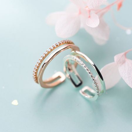 Stijlvolle zilveren en goudkleurige ringen met twee lagen uit de verstelbare set, weergegeven op een blauwe ondergrond.