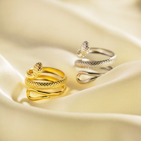 Roestvrijstalen Krasvrije Slangcurves Wikkelen Verstelbare Ringen Set van 5 - Een set van gouden en zilveren roestvrijstalen ringen met een ingewikkeld slangcurve-wikkeldesign, tentoongesteld op een luxueuze satijnen stof. Onderdeel van een krasvrije, verstelbare ringcollectie.