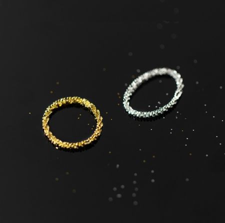 Una vista detallada del anillo de cadena minimalista en acabados de plata y oro, destacando la textura.