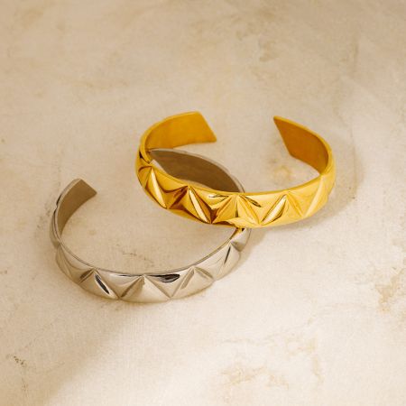 Detaljerad vy av guld- och silverarmbanden med deras intrikata triangulära mönster.
