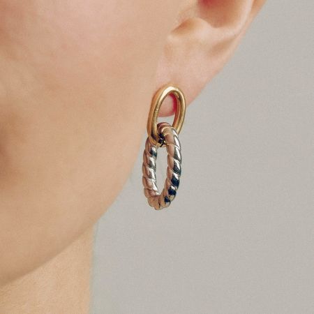 Twee-kleurige ovale twist oorbellen voor vrouwen - Chunky gouden en zilveren hypoallergene roestvrij staal - Model met de chunky twee-kleurige ovale twist oorbellen, die het elegante gouden en zilveren ontwerp op hypoallergene roestvrij staal toont.