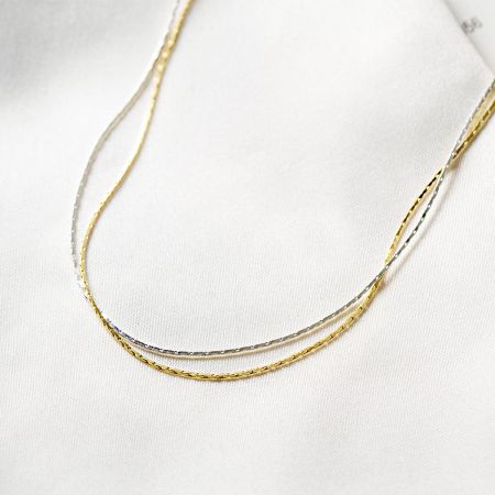 Vue détaillée des colliers en chaîne serpent entrelacés en or et en argent, soulignant la qualité de l'artisanat.