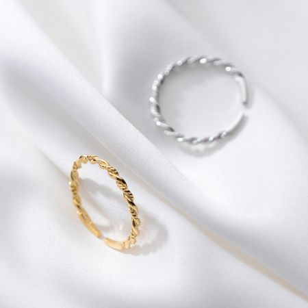 Detailed view of the gold and silver twisted rope rings on a white fabric background.