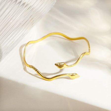 Vista lateral de la pulsera en forma de serpiente de color dorado que muestra su elegante diseño ondulado.