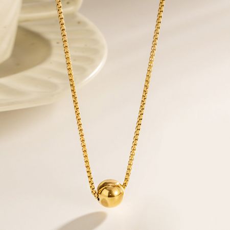 Collares de cadena de tirador de bola única dorada de acero inoxidable. - Un primer plano de un collar minimalista de acero inoxidable dorado con un pendant esférico liso en una delicada cadena de tirador.