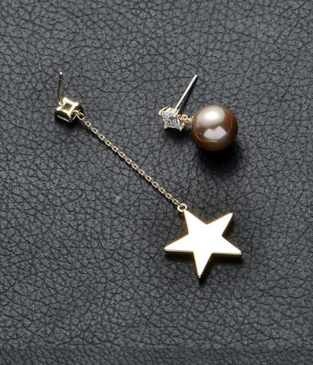Detaillierte Ansicht der Star Pearl Link Chain Ohrringe, die den hängenden goldenen Stern und den separaten Perlenstecker hervorhebt.