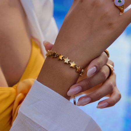 女性の手にあるステンレススチールのゴールドスターのブレスレットのクローズアップ。
