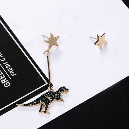 Vista detallada del par de pendientes asimétricos de estrella y dinosaurio.