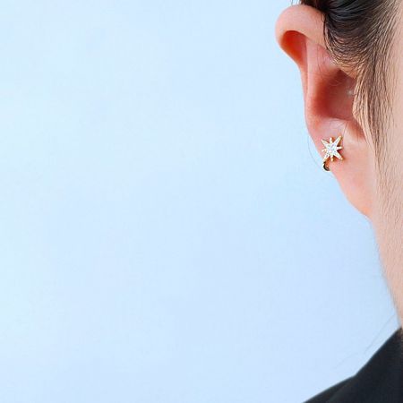 14k Gold Plated Star Non-Pierced Ear Cuff Earrings - A close-up of a woman wearing a delicate 14k gold-plated star-shaped ear cuff earring with a central white gemstone.