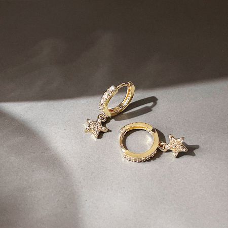 Angled shot of the pair of gold star huggie hoop earrings, showing their shine and craftsmanship.