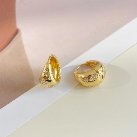 Two different styles from the earring set, one teardrop and one hoop, both adorned with star motifs and gemstones.