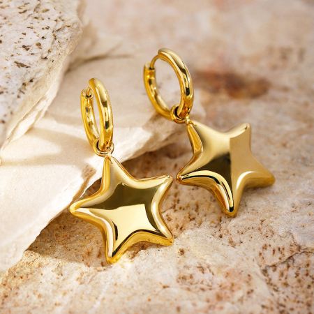 Scatto dettagliato degli orecchini huggie a pendente a stella d'oro.