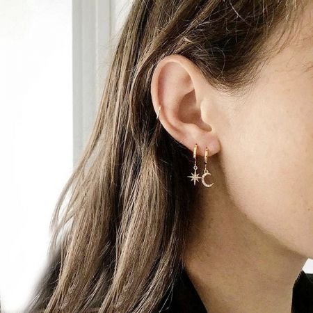 Een model met de gouden ster en halve maan asymmetrische hoepel oorbellen.