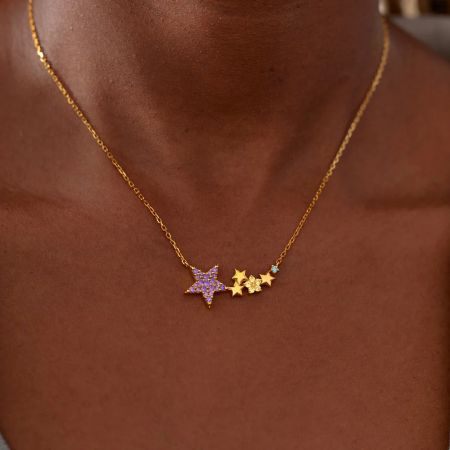A gold necklace with a delicate star-themed pendant on a white background.