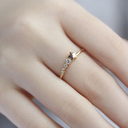 指に着用されたダイヤモンド付きの金の星リングで、そのスケールと輝きを示しています。