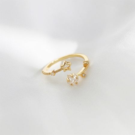 Un elegante anillo chapado en oro adornado con múltiples diseños de estrellas y piedras preciosas claras.