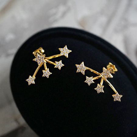 Boucle d'oreille mini étoile zircon brillante en argent sterling 925 (5 paires) - Une paire de boucles d'oreilles mini étoile en zircon en argent sterling 925 avec un sertissage griffes et une finition dorée, présentée sur une surface noire pour mettre en valeur leur éclat.