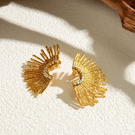 Un par de pendientes de diseño de sol dorado que exhiben las brillantes piedras blancas.