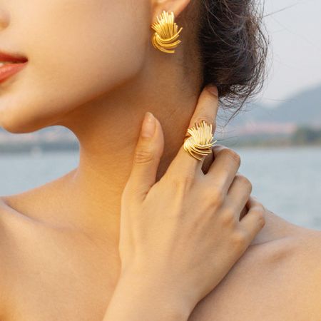 Un set abbinato di un anello d'oro a raggi di sole e orecchino, che mostra il design unico della collezione.