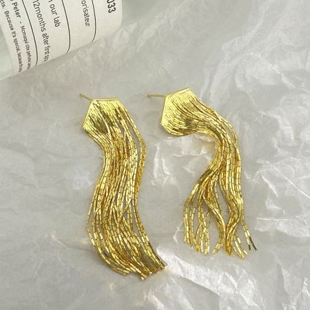 Un paio di orecchini a frangia lunga in oro con un design ondulato unico, esposti su uno sfondo bianco.