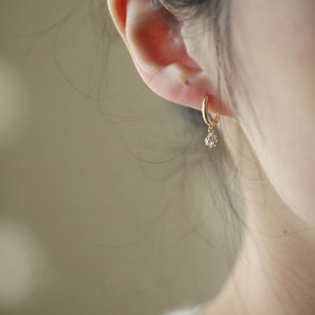Close-up of a gold teardrop crystal earring from the zircon dangle hoop set.