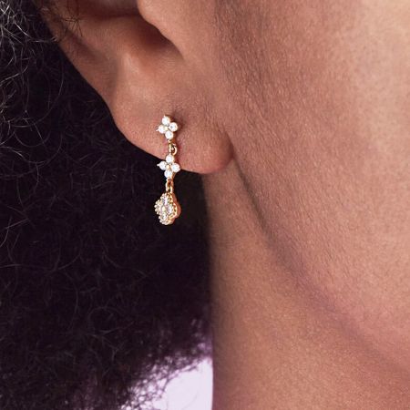 925 Sterling Zilveren Gouden Drievoudige Bloemenoorbellen - Een close-up van een vrouw die de 925 sterling zilveren gouden drievoudige bloemenoorbel draagt, die het elegante ontwerp en de druppelvormige hanger toont.
