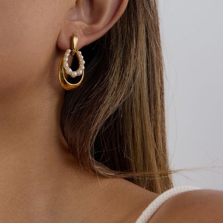 Conjunto de 5 pares de pendientes de perlas de acero inoxidable chapados en oro PVD. - Una mujer que lleva un elegante pendiente de perla de acero inoxidable chapado en oro PVD, mostrando su moderno diseño de gota ovalada y su idoneidad para el uso diario.