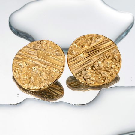 Gedetailleerde opname van de gouden stud oorbellen die de diagonale hamerslag textuur laat zien.