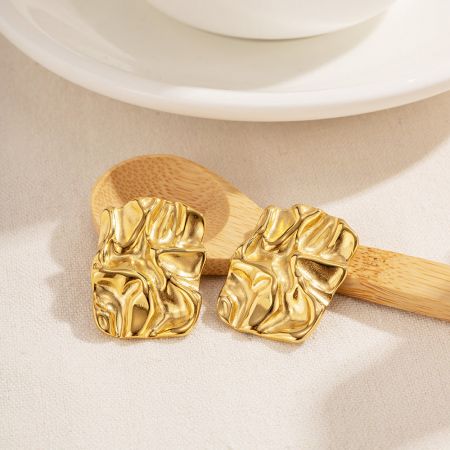 Pendientes de aro rectangulares gruesos de oro con un acabado texturizado, exhibidos en un plato blanco.