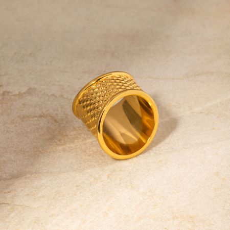 Närbild av en guldpläterad ring med en unik fiskhudstextur.