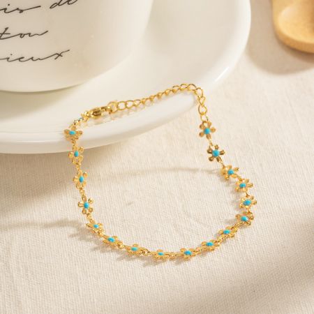Detaillierte Ansicht des goldenen Armbands mit türkisfarbenen Emaille-Blumenanhängern.