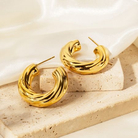 Pendientes de aro en forma de C retorcida de acero inoxidable chapados en oro. - Un par de pendientes de aro en forma de C retorcida de acero inoxidable chapados en oro sobre un fondo blanco limpio, mostrando su intrincado diseño.