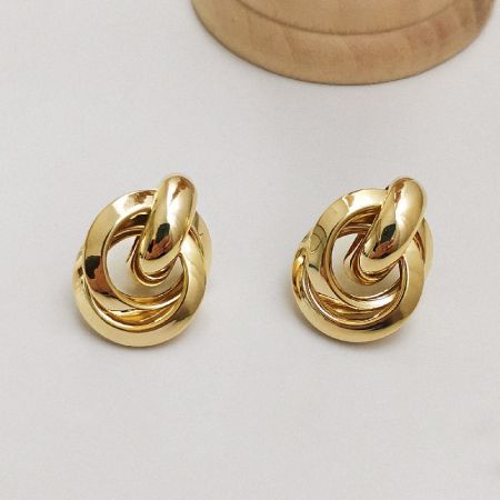 Scatto dettagliato degli orecchini a spirale attorcigliati in oro su uno sfondo pulito.
