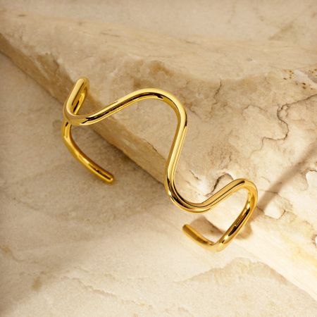 The stainless steel curve wave cuff bangle displayed on a chic marble surface, highlighting its modern design.
