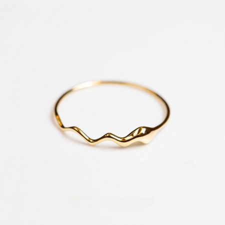 Een andere hoek van de elegante gouden golvende ring, die zijn unieke silhouet toont.