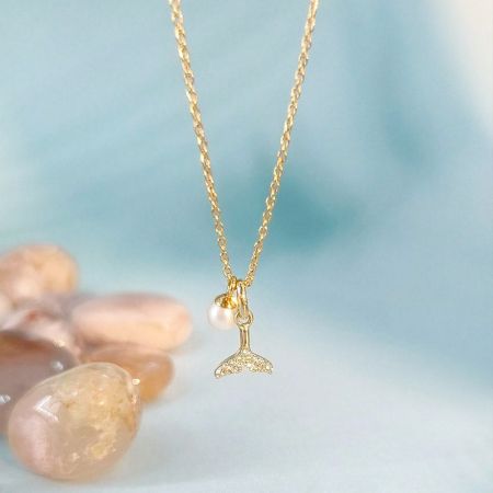 Queue de baleine en zircon en argent sterling 925 avec collier en perle en gros - Un gros plan du collier pendentif en argent sterling 925 en forme de queue de baleine en zircon, mettant en valeur l'accent délicat en perle et les cristaux scintillants sur la chaîne de couleur or.