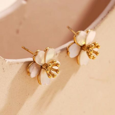 A pair of mother of pearl flower earrings with delicate gold accents.