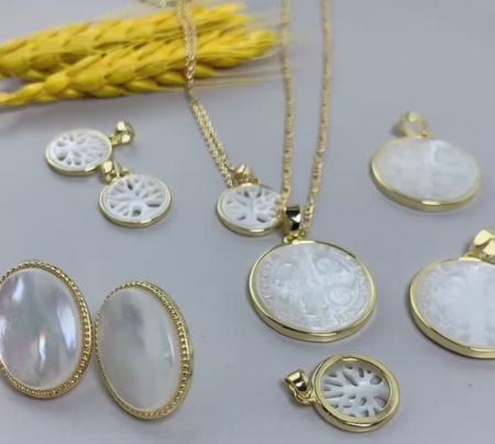 Una collezione di pezzi di gioielleria religiosa personalizzati, che mostrano vari design e stili di pendenti in madreperla.