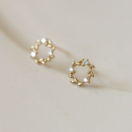 Orecchini a bottone semplici a forma di corona d'oro piccoli in argento sterling 925 (5 paia) - Un primo piano degli orecchini a bottone a forma di corona d'oro piccoli in argento sterling 925, evidenziando il design intricati delle foglie e le pietre bianche scintillanti.