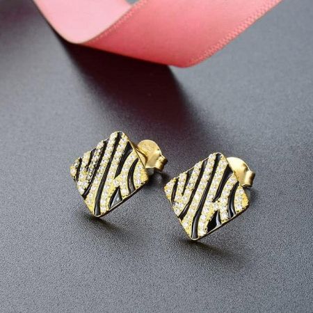 Un paio di orecchini a strisce di zebra con pietre scintillanti su uno sfondo scuro.