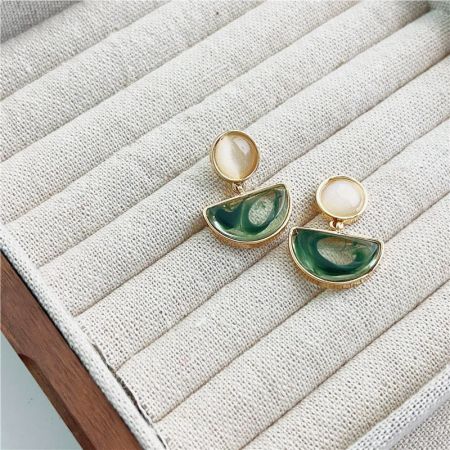 緑と白の石のアクセントがある金のイヤリングのクローズアップ。