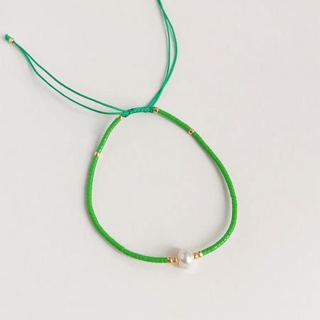 Un delicato braccialetto in corda verde con una sola perla e dettagli in oro.